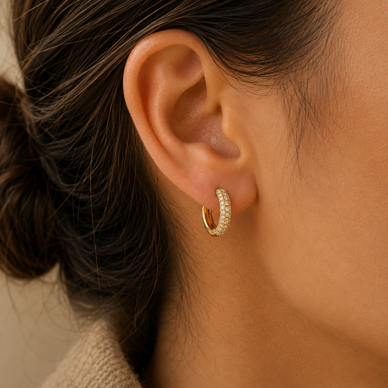 Model wearing gold pavé huggie hoop earring